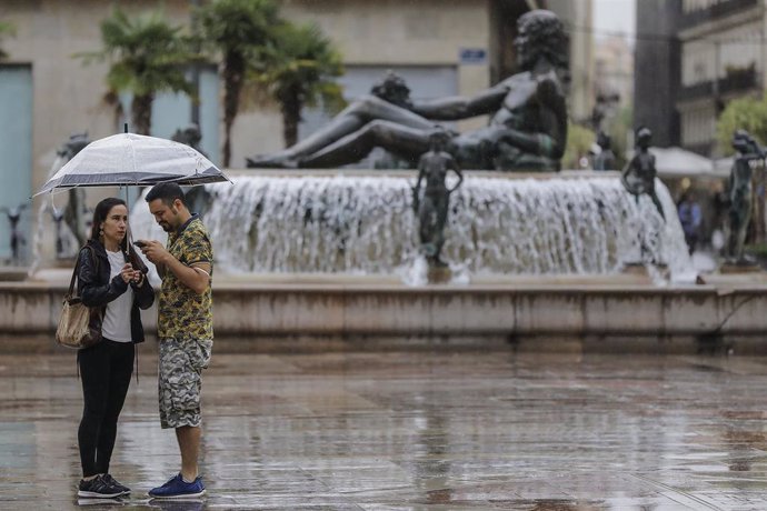 Archivo - Varias personas sostienen un paraguas mientras llueve en imagen de archivo