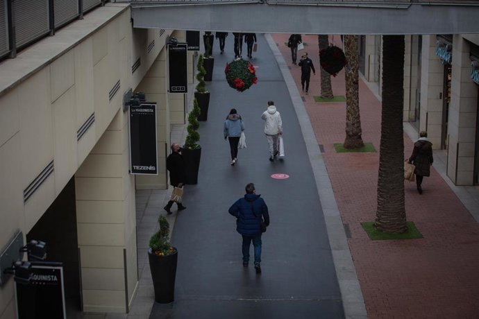 Archivo - Varias personas realizan compras en un centro comercial