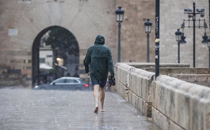 Archivo - Una persona camina bajo la lluvia