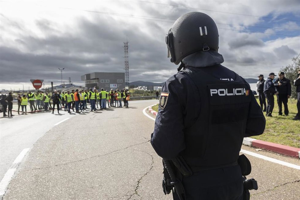 Un agente de Policía Nacional frente a agricultores en la rotonda de Agricultura de Mérida que conecta la A-5 con la nacional 630