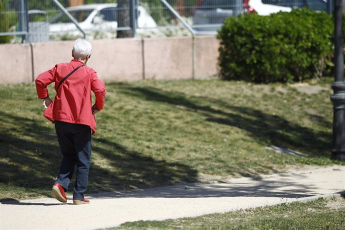 Archivo - Una mujer jubilada paseando por un parque de Madrid