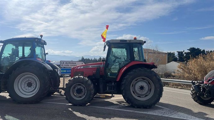 Tractores en la carretera delante de un cartel indicativo de La Almunia.