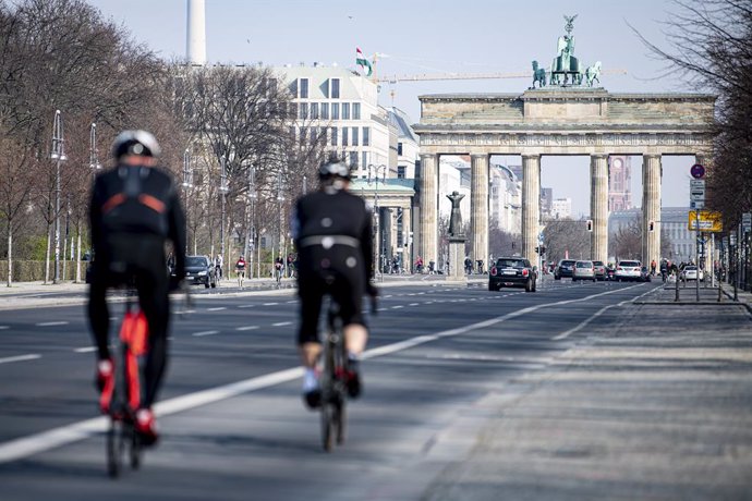 Archivo - 28 March 2020, Berlin: Two cyclists ride on the Strasse des 17. Juni (17th of June Street) in the direction of the Brandenburg Gate. In order to slow down the spread of the coronavirus (COVID-19), the federal government has considerably restrict