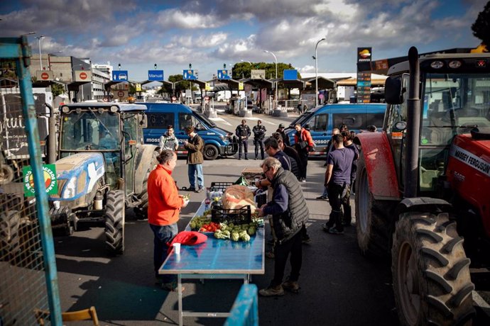 Agricultores y tractores ponen alimentos sobre una mesa durante una concentración en la entrada de Mercabarna