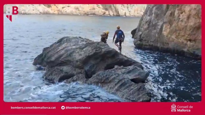 Dos bomberos participan en el rescate de un cabrito aislado en una roca.