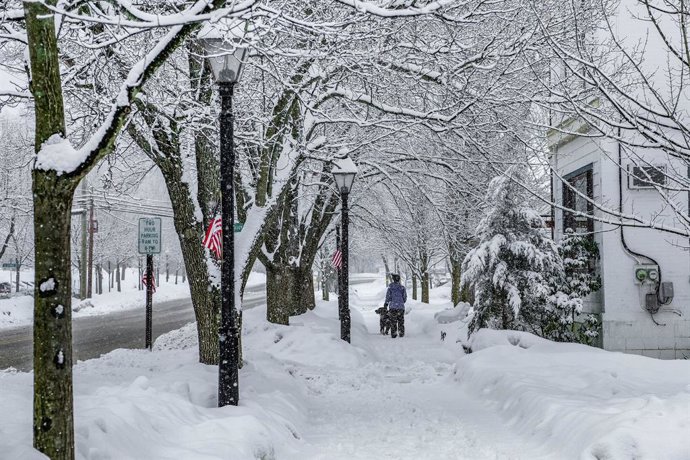 Archivo - 22 February 2021, US, Milford: A woman walks her dog on a snow-covered sidewalk amid heavy snowfall. Photo: Preston Ehrler/SOPA Images via ZUMA Wire/dpa