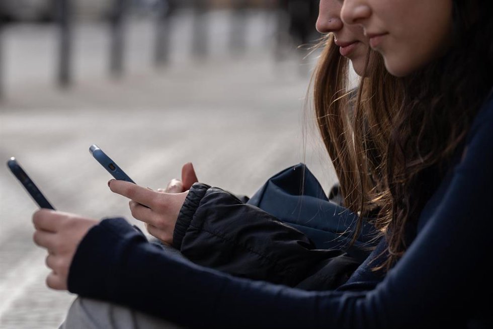 Dos personas usan el teléfono móvil, a 1 de febrero de 2024, en Barcelona, Cataluña (España). 