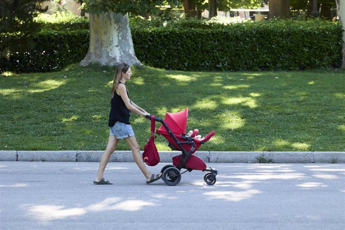 Archivo - Una persona pasea con un carrito de bebé en el parque de El Retiro.