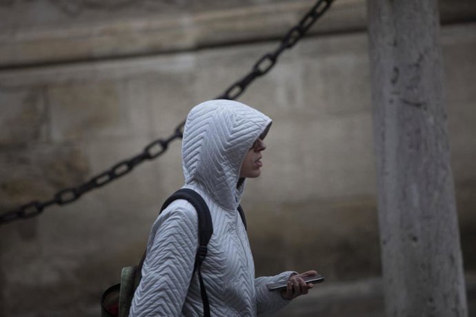 Archivo - Una mujer se coloca la capucha para protegerse de la lluvia