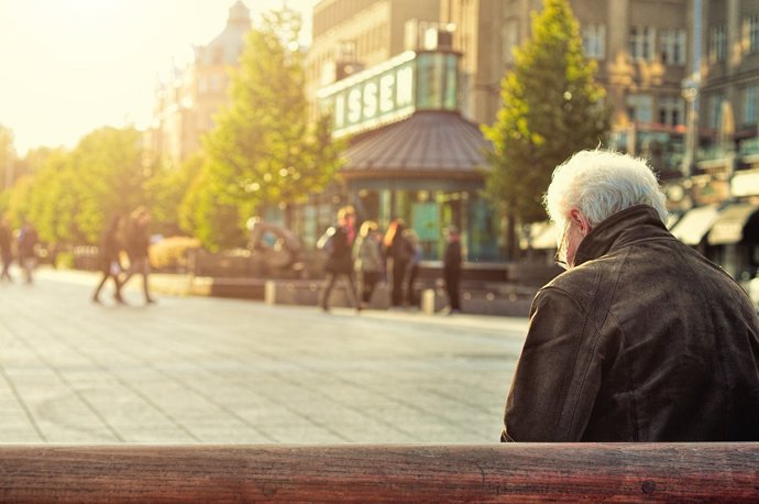 Archivo - Una persona mayor está sentada en un banco.