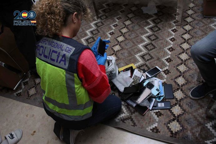 Una agente de la Policía Nacional interviene varios de los móviles hallados en uno de los registros