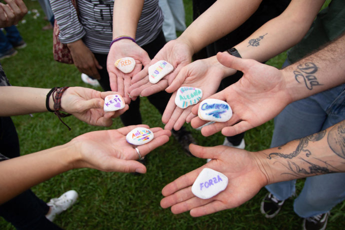 Archivo - Un grupo de personas sostienen unas piedras con palabras como 'amistad', 'alegría', 'confianza' y 'forza'.