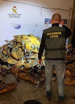 Un agente de la Guardia Civil junto a parte de los jamones robados de una empresa distribuidora de productos de alimentación de Santomera (Murcia)