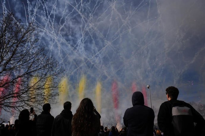 Varias personas observan el humo de colores durante la primera masclet madrileña, en el Puente del Rey de Madrid Río, a 18 de febrero de 2024, en Madrid (España). 