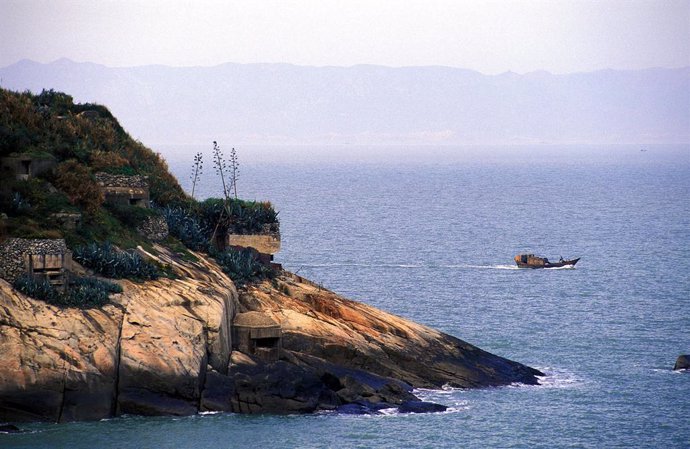 Archivo - Aug 10, 2002; Kinmen Island, Taiwan; Heavily fortified coastline of Matzu Island, Taiwan, with Mainland China's coastline rising int he distance.  A fishing boat passes by: for generations the Matzu natives have made a living by smuggling good