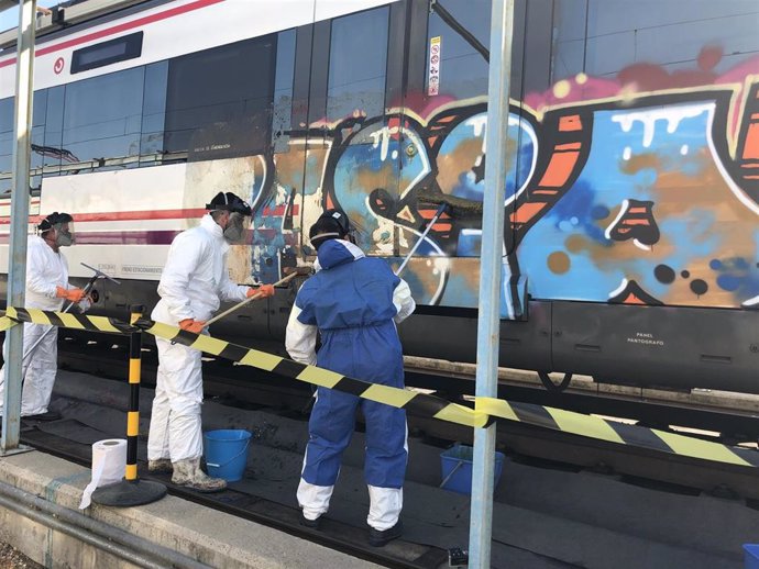 Archivo - Operarios limpian un grafiti en un tren de Cercanías de Madrid