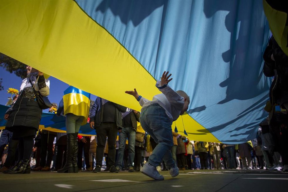 Archivo - February 26, 2023, Madrid, Spain: A boy runs under a giant Ukrainian flag, during a march through the streets of Madrid, organized by associations of Ukrainians in Madrid to demand an end to the war on the first anniversary of the start of the