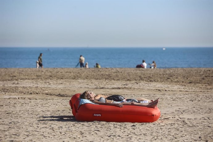 Una dona pren el sol tombada en un flotador, a la platja de la Malvarrosa, a 25 de gener del 2024. 