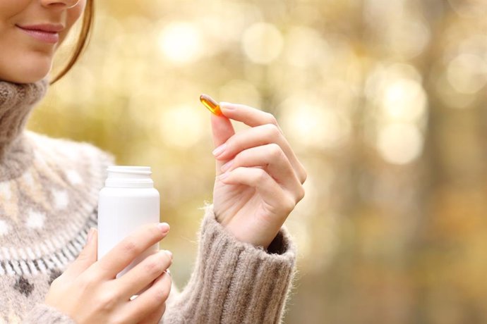 Archivo - Mujer tomando una pastilla de vitaminas en invierno.