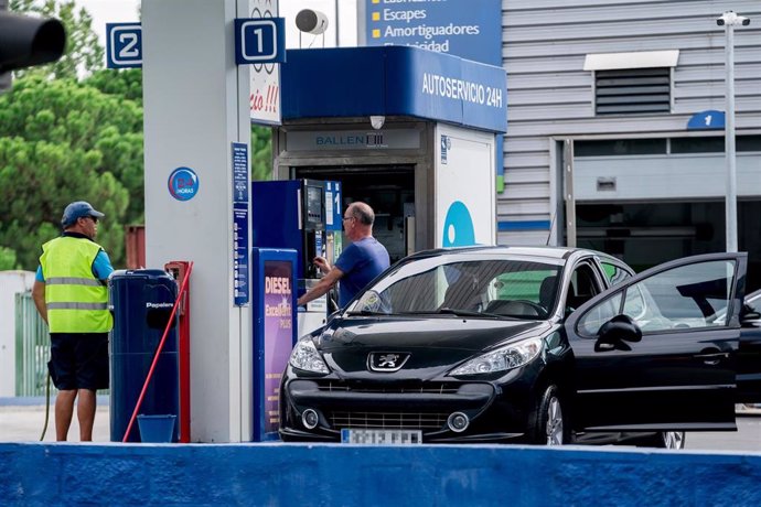 Archivo - Un hombre echa carburante a su vehículo en una estación de servicio.
