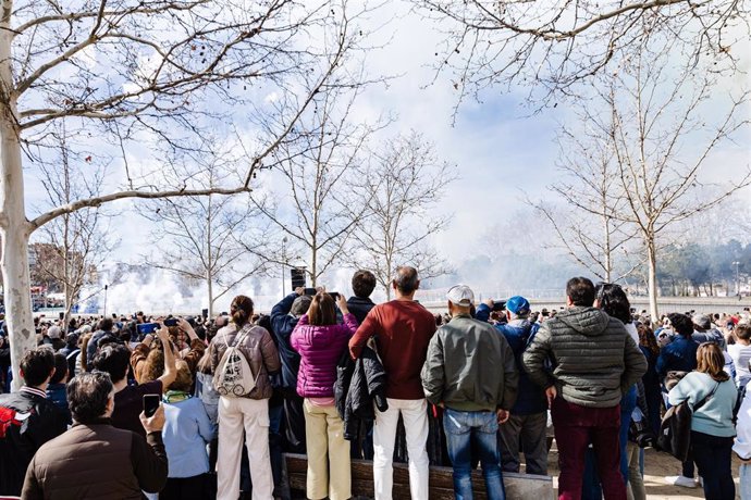 Decenas de personas observan el humo durante la primera masclet madrileña, en el Puente del Rey de Madrid Río