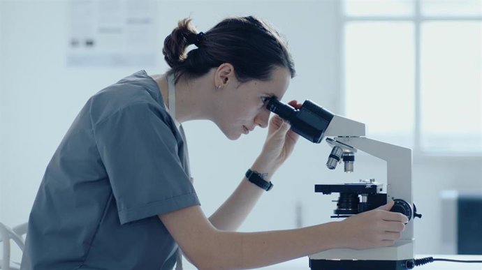 Investigadora mirando por un microscopio