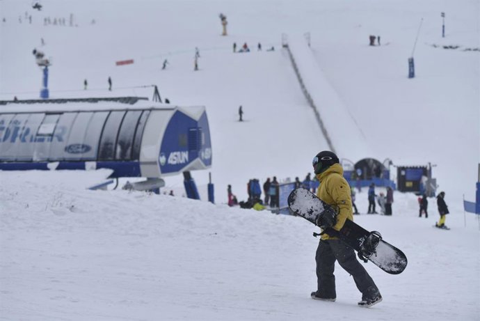 Archivo - Una persona con una tabla de snowboard, en el día que comienza la temporada de esquí, en la estación de Astún, a 3 de diciembre de 2022, en xx, Huesca, Aragón (España).
