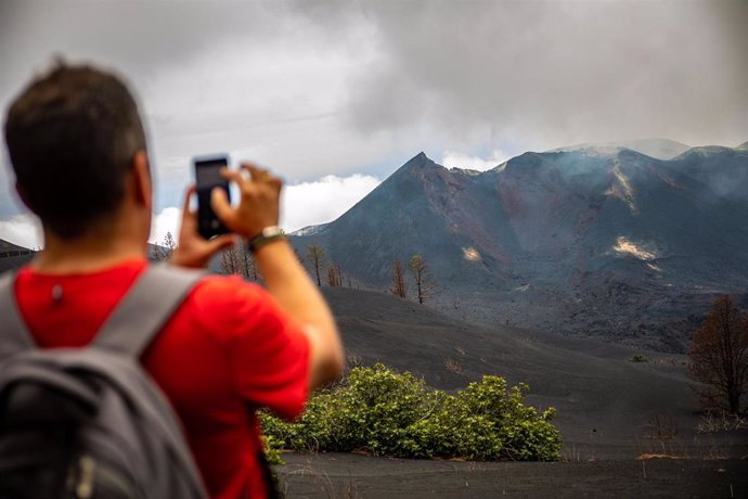 Archivo - Un turista hace una fotografía en un sendero afectado por la lava del volcán de Tajogaite, en La Palma