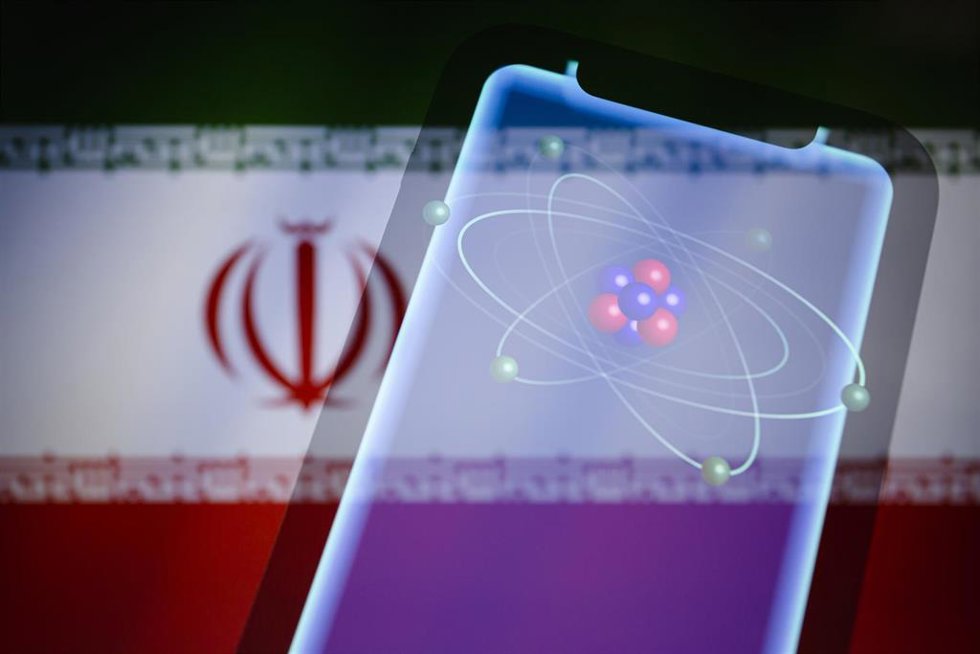 Archivo - Representación visual del átomo, electrones en orbitales, neutrones y protones en el núcleo, mostrada en un teléfono inteligente con la bandera de Irán recortada de fondo.