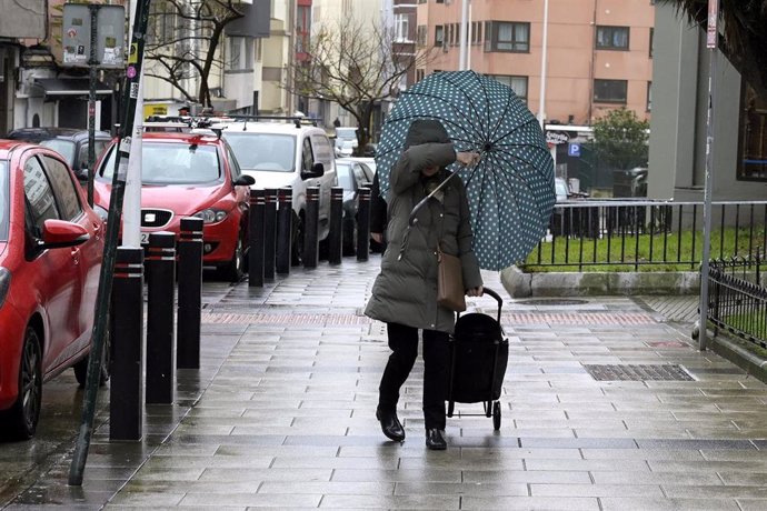 Una mujer se refugia del viento con paraguas, a 8 de febrero de 2024, en A Coruña, Galicia (España). El paso de la borrasca Karlotta por Galicia está provocando a lo largo del día de hoy incidencias, lluvias copiosas y vientos de mucha intensidad, que han