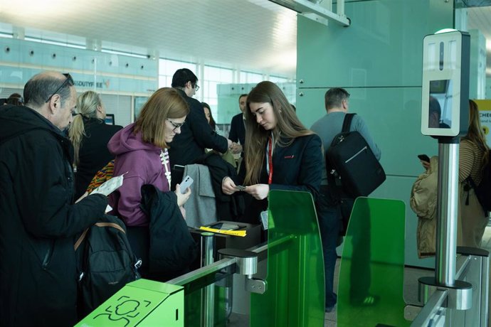 Archivo - Una joven chequea los billetes de los pasajeros en la puerta de embarque, en el Aeropuerto de Barcelona-El Prat.