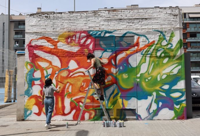 Dos artistas pintando el centro de transformación que hay en la calle Gasòmetre