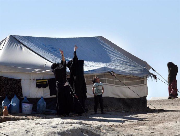 Archivo - November 8, 2019, Al-Hol, Hasakah Province, Syria: Two female campers and  black hijabs point to the sky and a little boy looks up to. A chain-link fence barely surrounds the al-Hol camp for ISIS-affiliated families in eastern Syria. It houses f