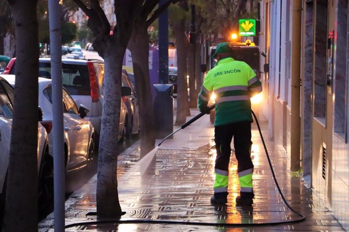 Un operario baldea una calle