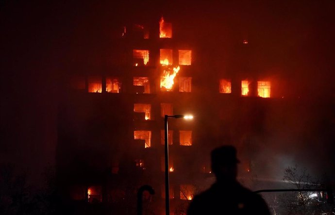 Un agente observa el edificio en llamas, en el barrio de Campanar, a 22 de febrero de 2024, en Valencia, Comunidad Valenciana (España). Un incendio de grandes dimensiones ha arrasado un edificio de 14 plantas en el barrio valenciano de Campanar. El fuego,