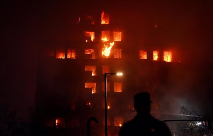 Un agente observa el edificio en llamas, en el barrio de Campanar, a 22 de febrero de 2024, en Valencia, Comunidad Valenciana (España). Un incendio de grandes dimensiones ha arrasado un edificio de 14 plantas en el barrio valenciano de Campanar. El fuego,