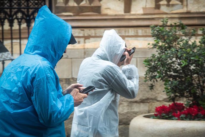 Dos personas se protegen de la lluvia con un impermeable