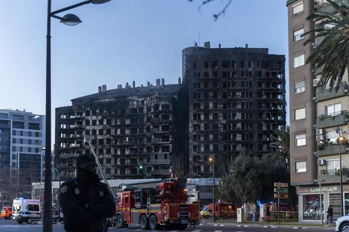 Bomberos y un agente de Policía Nacional en las inmediaciones del edificio incendiado