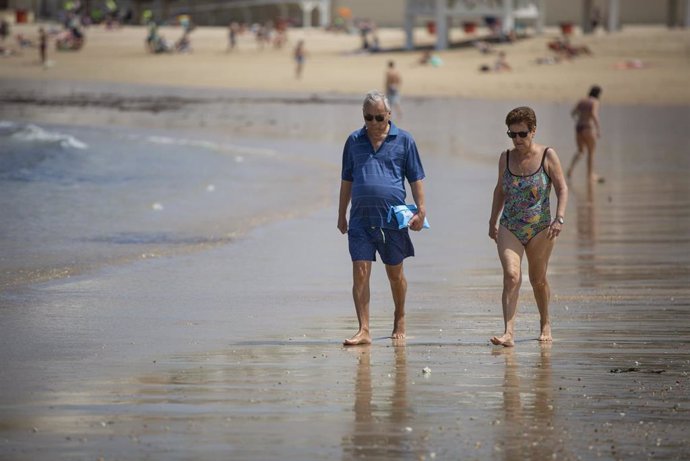Archivo - Personas paseando en la playa de La Caleta.