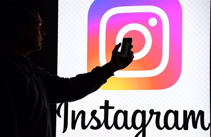 Archivo - FILED - 15 March 2019, Schleswig-Holstein, Aukrug-Homfeld: A person holds a smartphone in front of a monitor with the logo of social media platform Instagram. Photo: Carsten Rehder/dpa/Archivbild