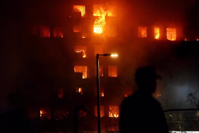 Un agente observa el edificio en llamas, en el barrio de Campanar, a 22 de febrero de 2024, en Valencia, Comunidad Valenciana (España). 