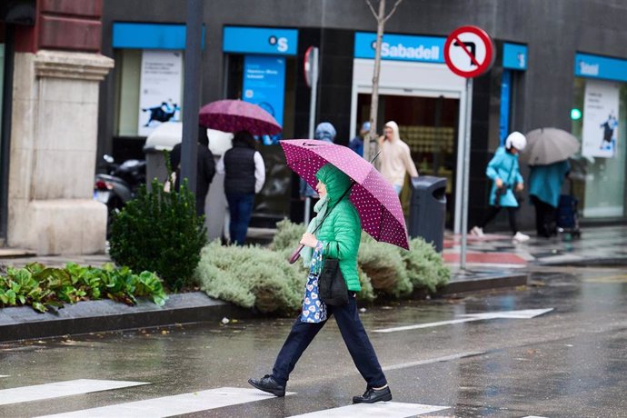 Archivo - Una persona se cubre de la lluvia y el viento con paraguas, en Santander, Cantabria (España). 