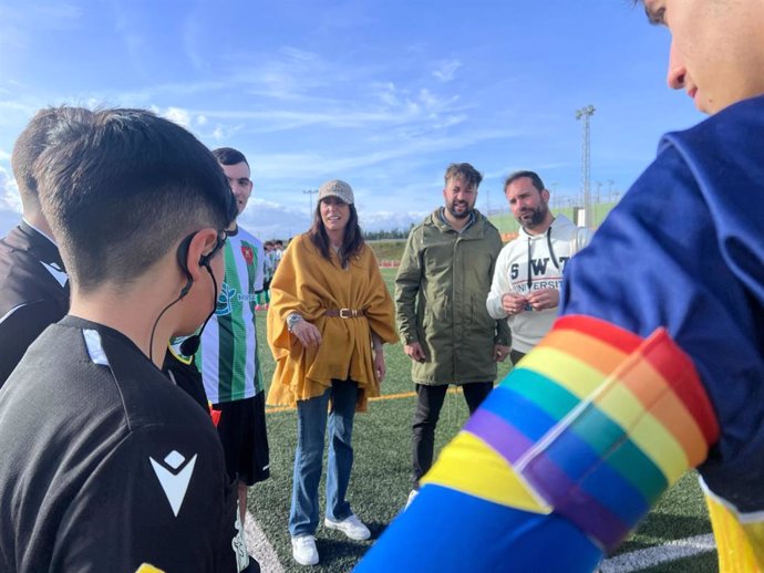 Loles López entrega en Valverde del Camino (Huelva) brazaletes con la bandera LGTBI en un partido de fútbol juvenil.