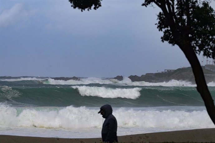 Una persona camina delante de las olas durante el frente meteorológico, a 23 de febrero de 2024, en A Coruña, Galicia (España). 