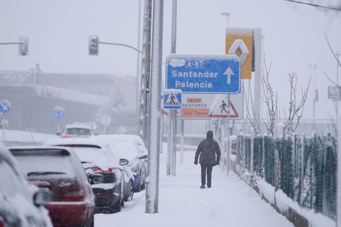 Una persona camina por una calle cubierta de nieve, a 18 de enero de 2023, en Cantabria (España)