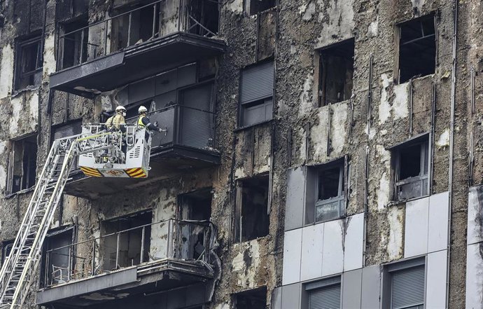 Bomberos en una grúa sanean la fachada quemada, a 26 de febrero de 2024, en Valencia, Comunidad Valenciana (España). Un incendio de grandes dimensiones arrasó el pasado 22 de febrero un edificio de 14 plantas en el barrio valenciano de Campanar. El fueg