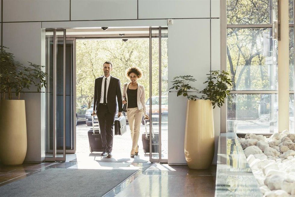 Archivo - Viajeros de negocios entrando en un hotel con sus maletas.