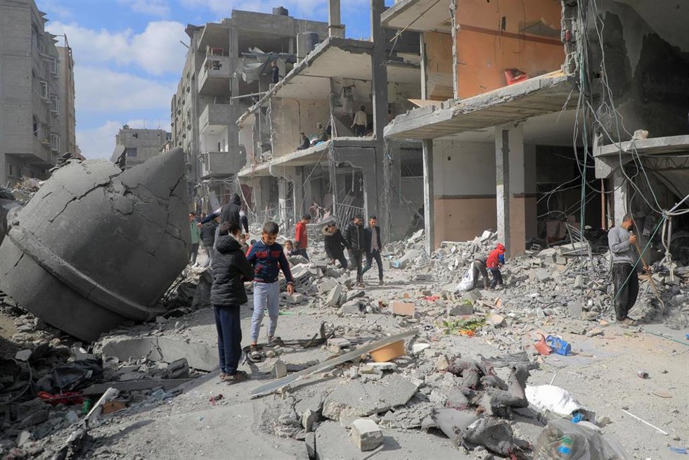Un grupo de personas pasean entre los escombros de un edificio en la ciudad de Rafá, en el sur de la Franja de Gaza