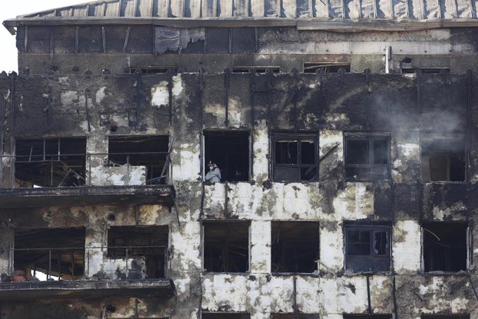 Un agente de la Policía Científica busca las causas del incendio en el edificio del barrio de Campanar