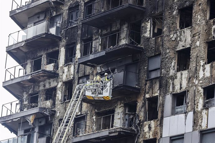 Bombers en una grua sanegen la façana cremada de l'edifici de Campanar
